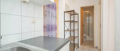 Una cocina moderna con un lavamanos de acero inoxidable, armarios blancos y un cuadro abstracto morado.