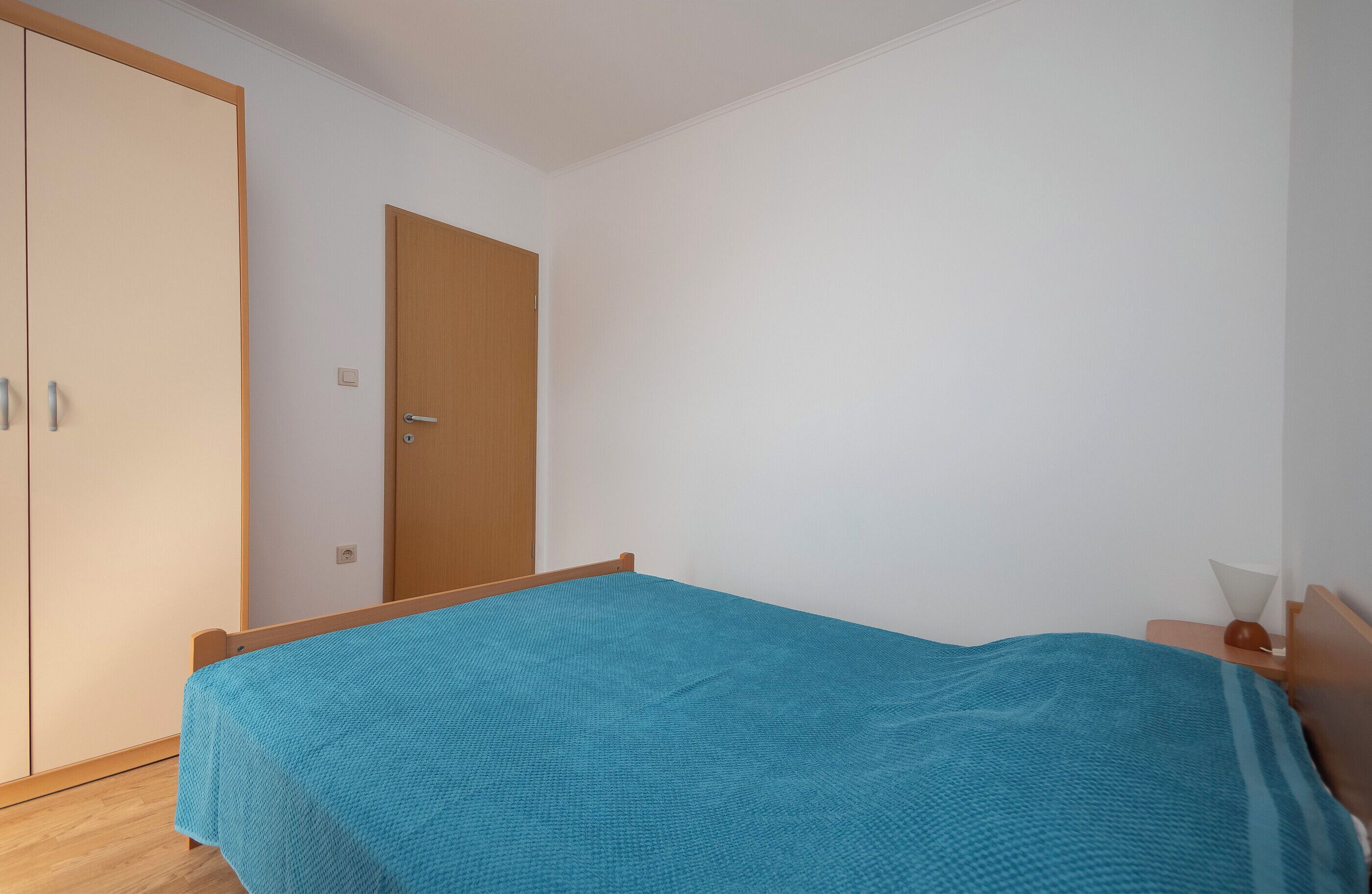 A bedroom with a bed, a wardrobe, and a door.