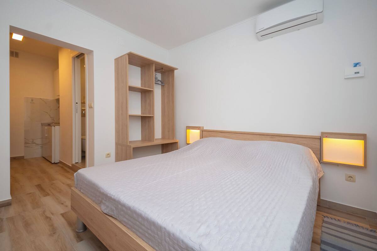 Ett sovrum med en säng i trä, inbyggda hyllor, en luftkonditionering och sänglampor.