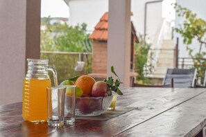 Ein Holztisch mit einer Kanne Orangensaft, zwei Gläsern und einer Obstschale.