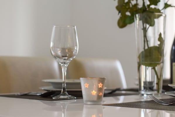 A dining table with a candle holder, a glass candle, and a vase with a plant. - Apartment Pocrnja (Rogoznica)