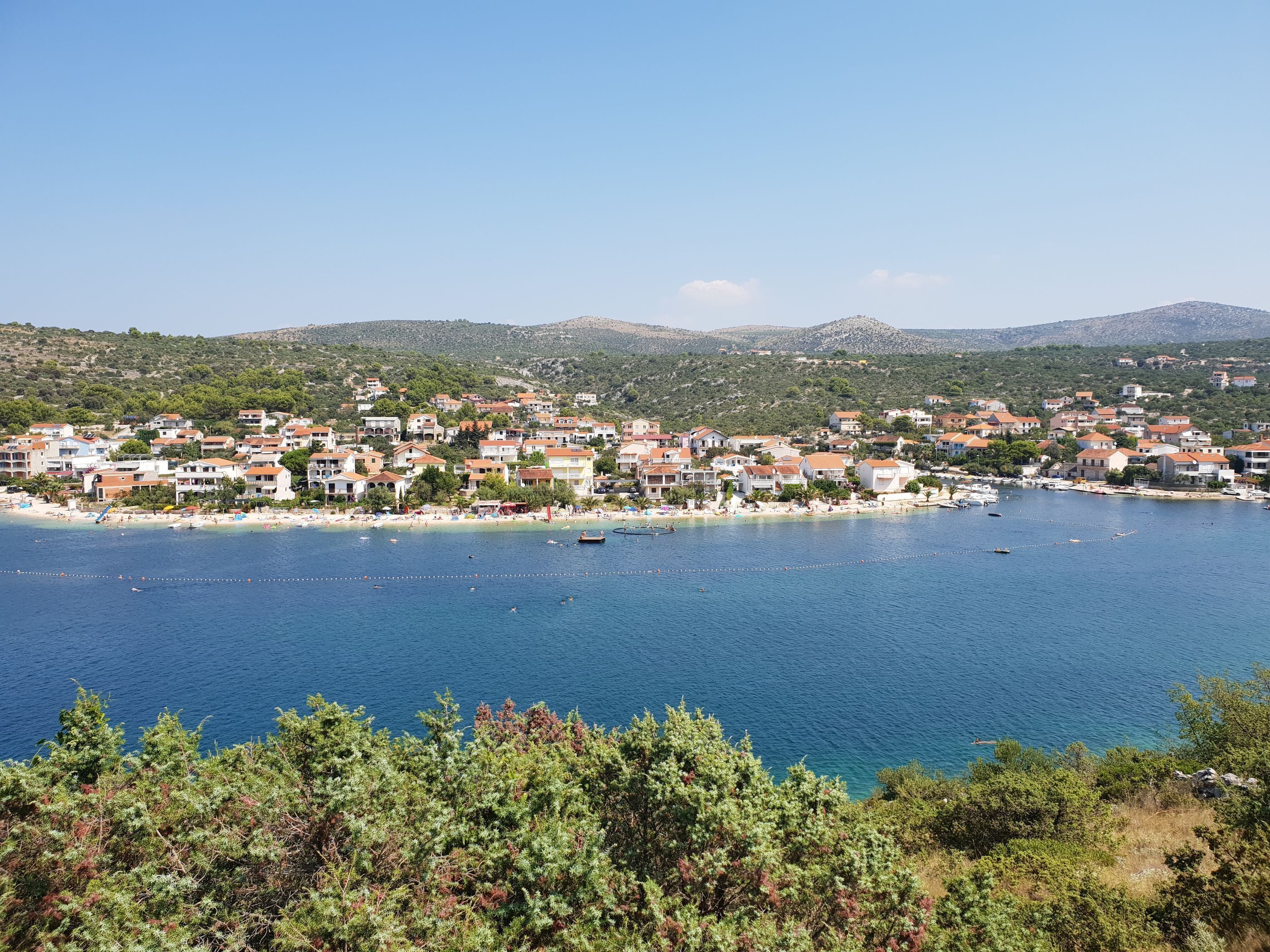 A coastal town with buildings along the shoreline, a beach, and boats in the water.