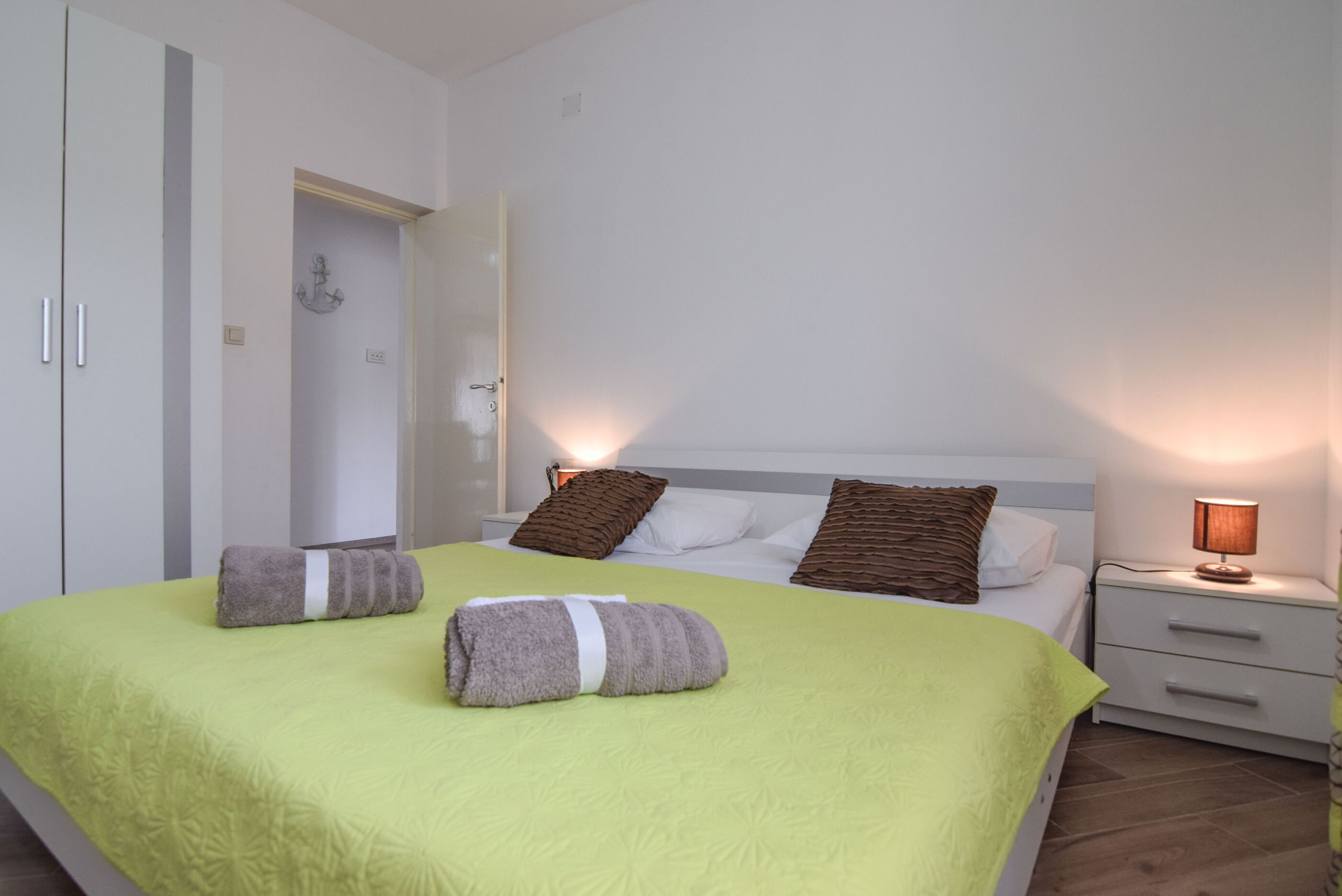 Ein Hotelzimmer mit Bett, zwei Kissen, einem Nachttisch, einer Lampe und einem Kleiderschrank.