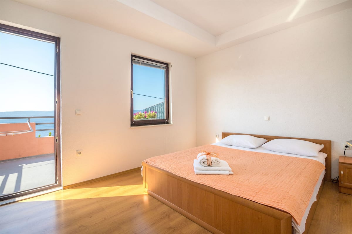 Une chambre à coucher avec un lit en bois, une fenêtre donnant sur un beau paysage et un balcon.