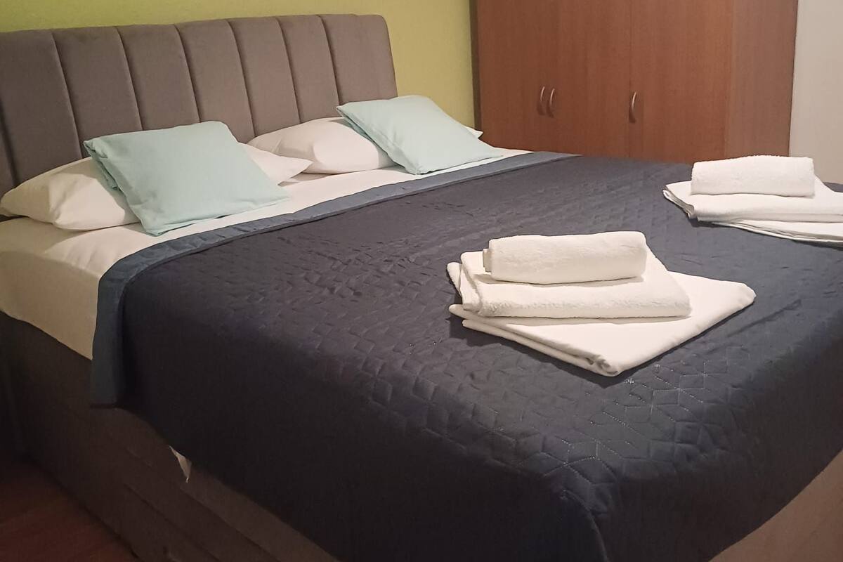 Une chambre à coucher avec un lit, des oreillers, une armoire en bois et des serviettes soigneusement pliées.