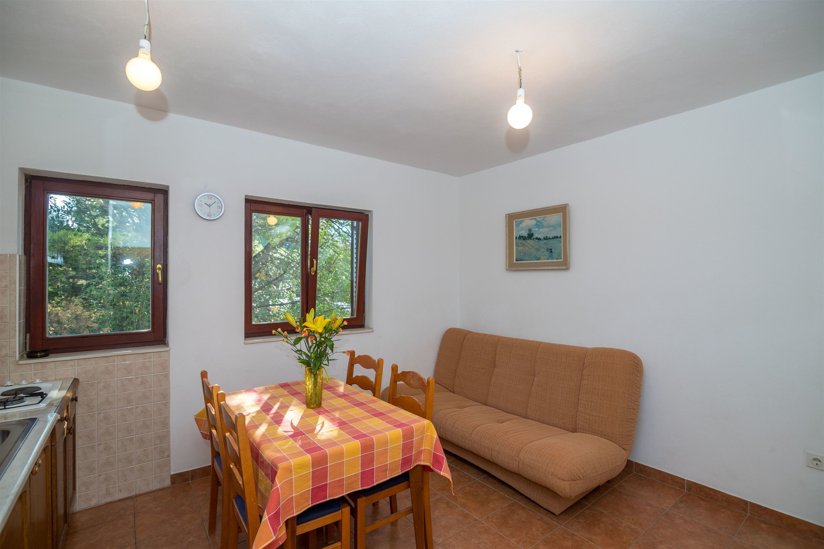 Una cocina con una mesa de comedor, sillas, un sofá y dos ventanas con cortinas.