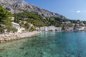 Una cittadina costiera con acque cristalline, edifici lungo la riva e montagne sullo sfondo.