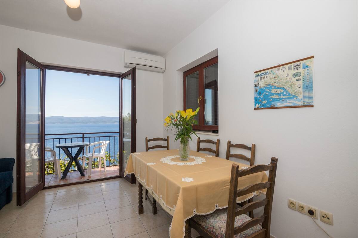 A dining area with a table and chairs, a vase with flowers, and a map on the wall.
