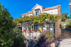 A traditional stone building with a tiled roof, a stone staircase, and a metal fence. - House Dobrila (Igrane)
