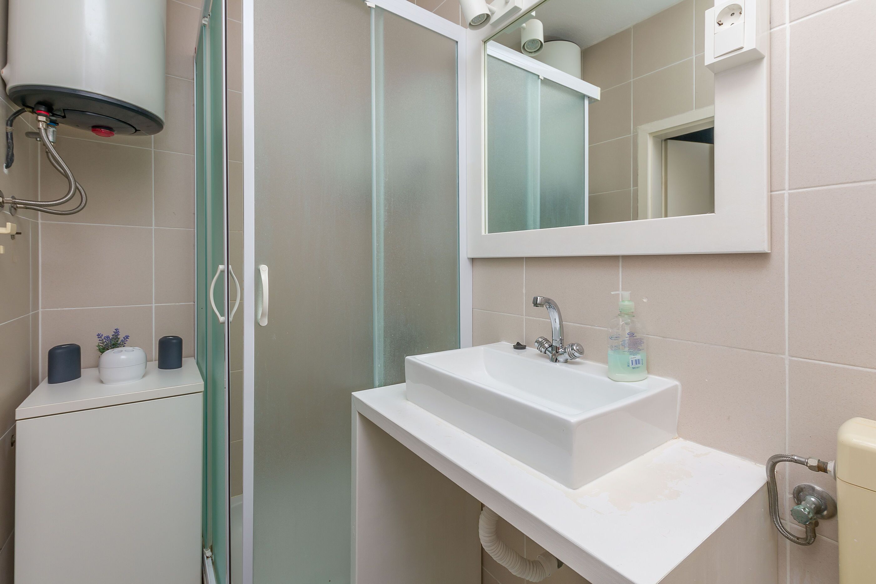 A bathroom with a white sink, a mirror, and a shower enclosure.