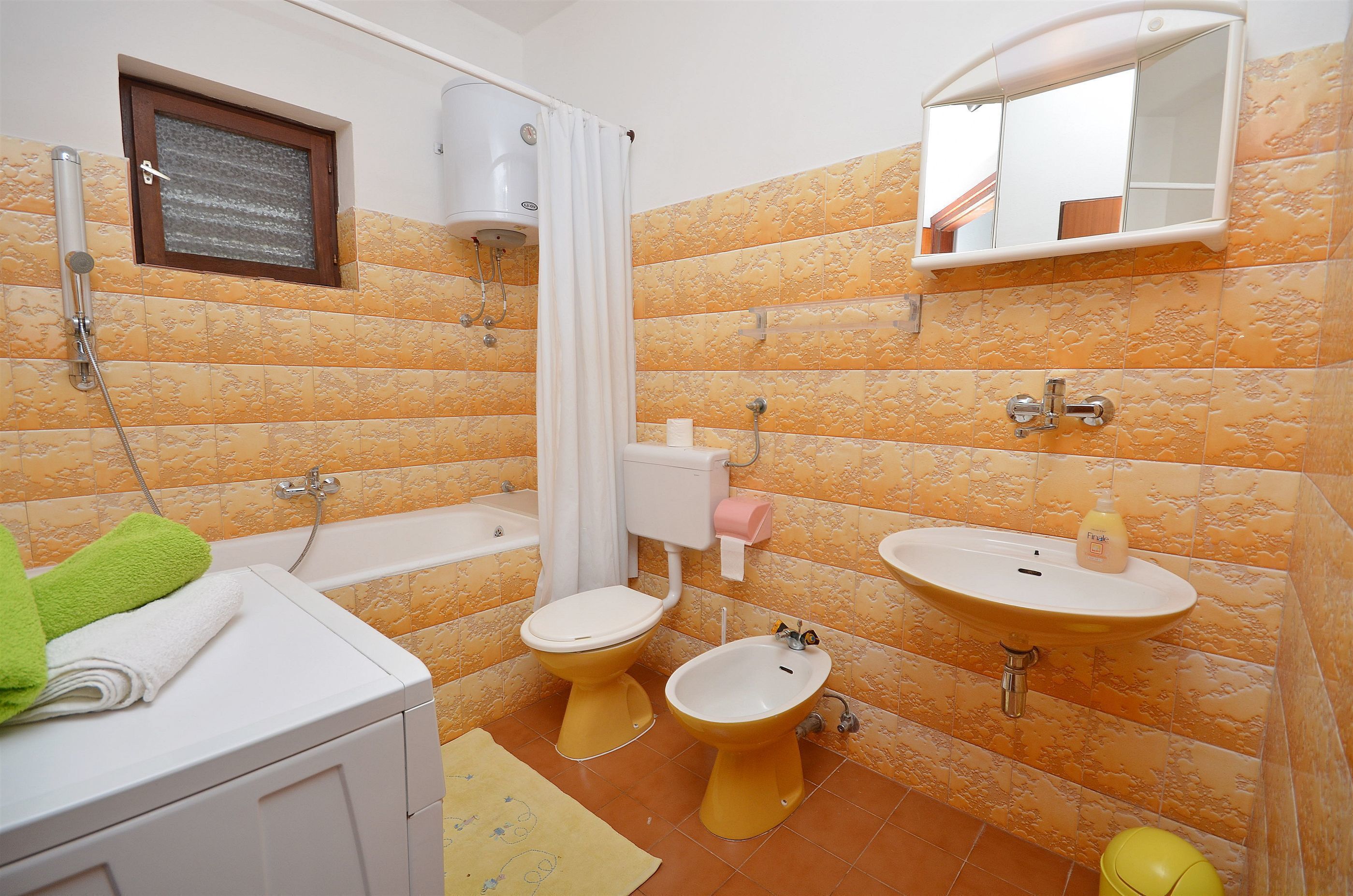 Een badkamer met een badkuip, twee toiletten, een wastafel en een douche.