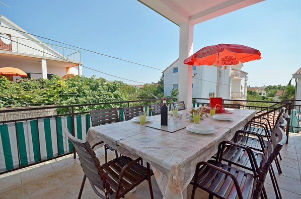 An outdoor dining area with a table set for four, surrounded by chairs, and an umbrella providing shade.