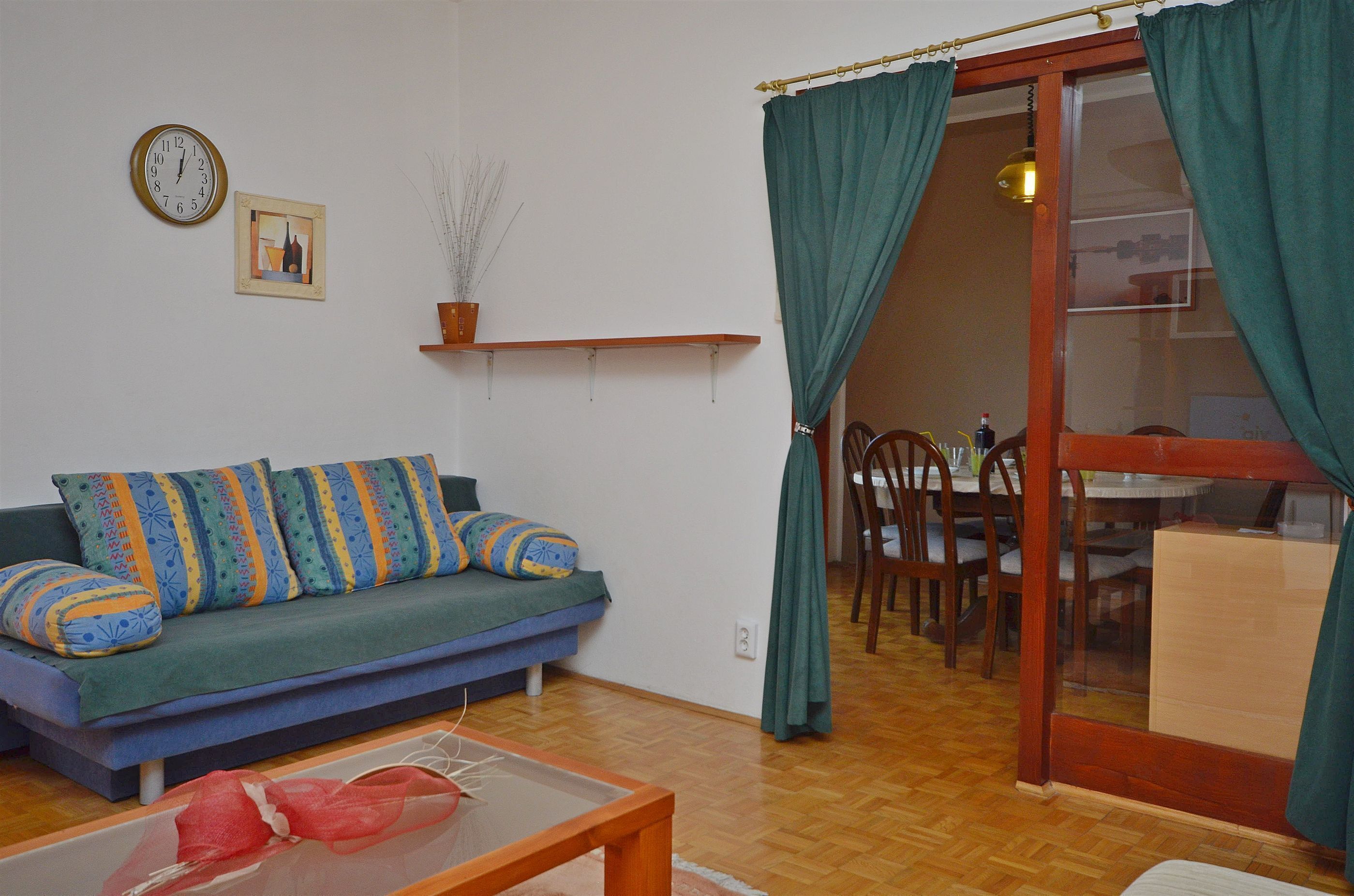 Una sala de estar con un sofá azul, una mesa de centro de madera y un comedor con sillas y una mesa de madera.