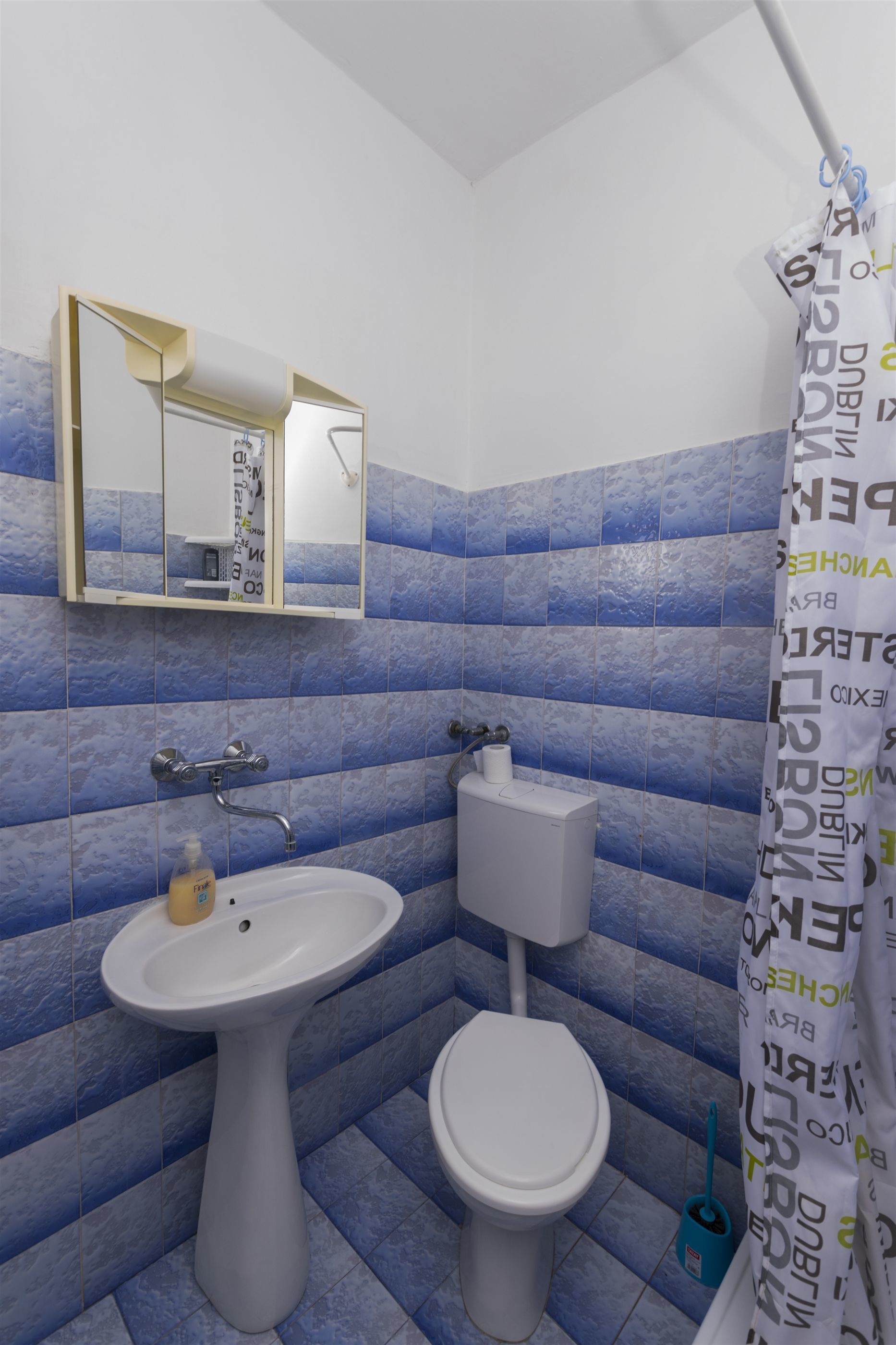 A bathroom with a pedestal sink, toilet, and a mirror above the sink.