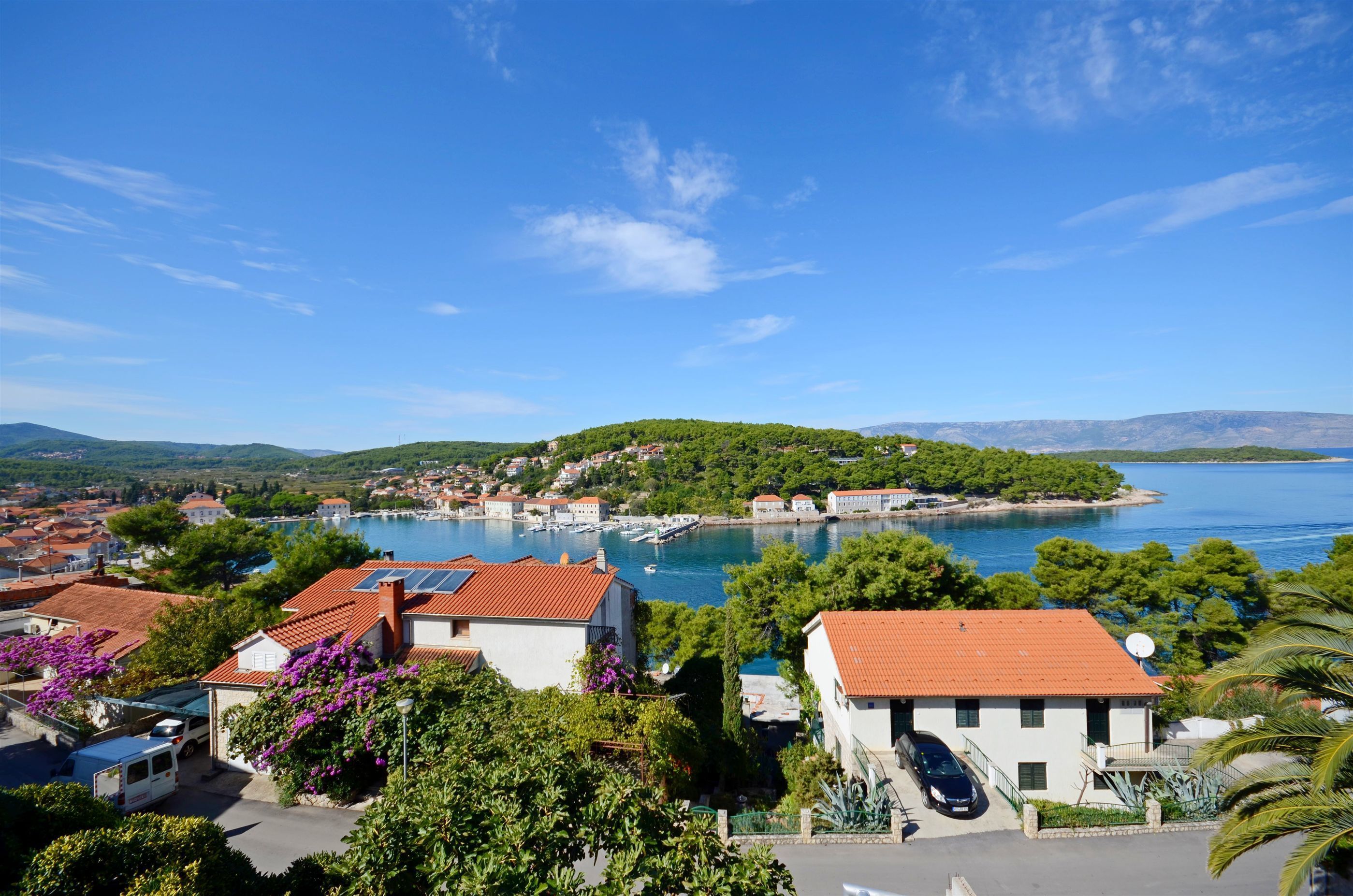 Une ville côtière avec des bâtiments, un port de plaisance et un ciel bleu dégagé.