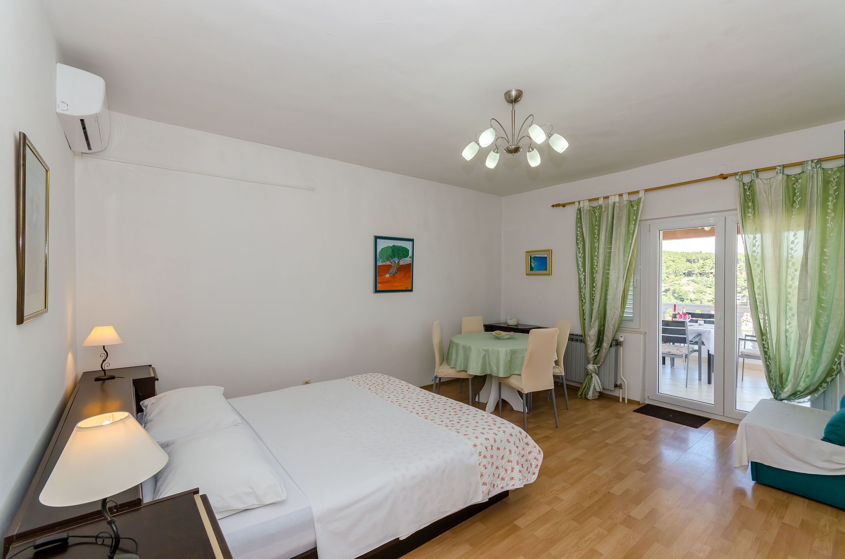 Habitación de hotel con cama, lámpara de noche, escritorio, silla y vistas a través de un ventanal.
