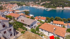 A coastal town with buildings, a marina, and a hilly backdrop. - Apartments Jakov (Jelsa)