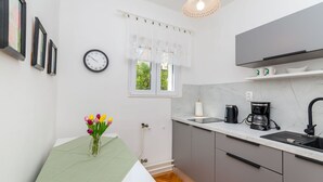 A modern kitchen with a sink, coffee maker, and a window with curtains. - Apartments Jakov (Jelsa)