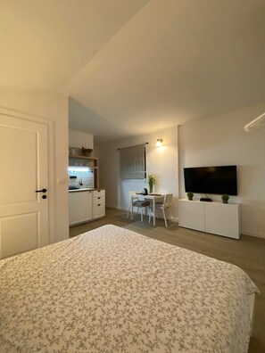 A bedroom with a bed, a television, a dining area with a table and chairs, and a kitchenette. - Apartments Mirko (Seget Vranjica)