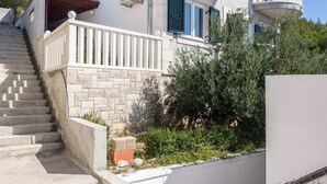 Un edificio su due piani con un balcone, una scala che conduce al piano superiore e un piccolo giardino.