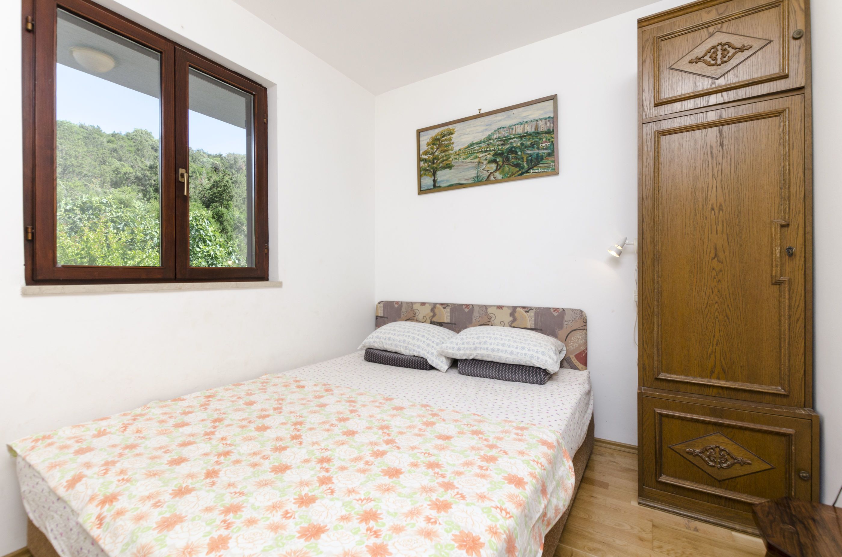 Una camera da letto con un letto, una finestra, un quadro e un armadio.