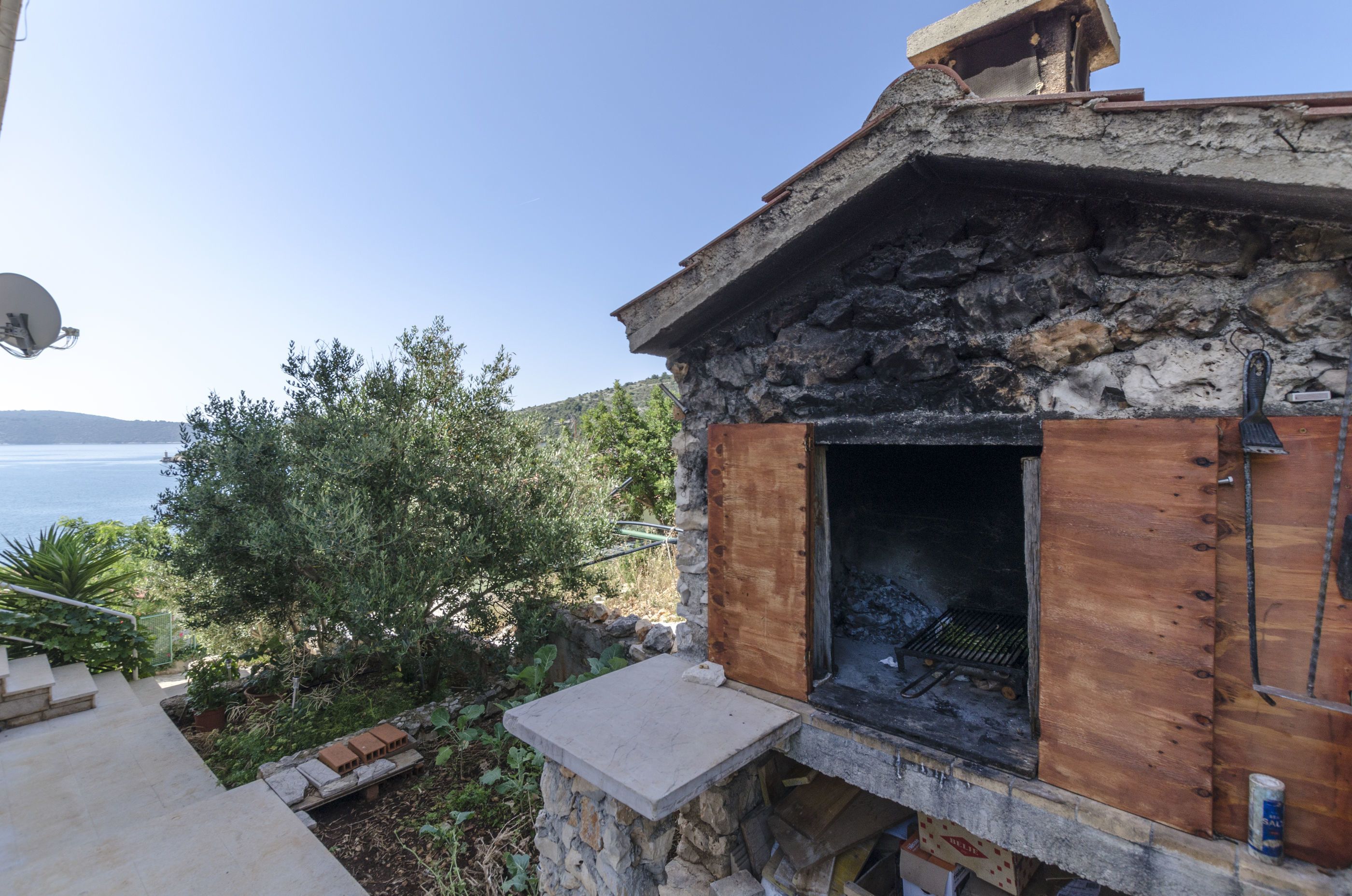 A stone building with a wooden door and a grill outside.