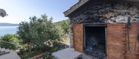 A stone building with a wooden door and a grill outside.