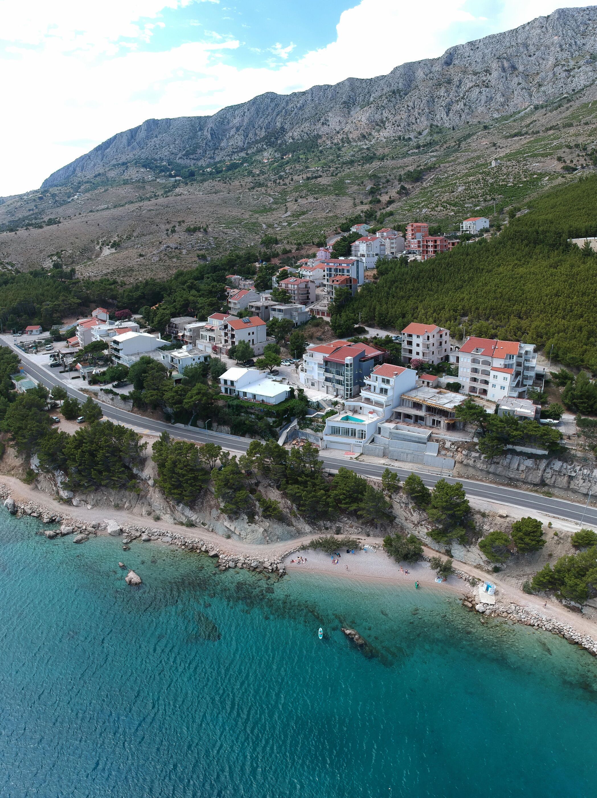 An aerial view of a coastal town with buildings, a road, and a beach.
