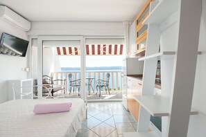 A hotel room with a bed, a TV, a balcony with chairs and a table, and a view of the sea. - Apartments Gordana (Lokva Rogoznica)