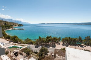 A coastal view with a clear blue sea, a road, and a building with a pool. - Apartments Gordana (Lokva Rogoznica)