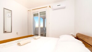 Ein Hotelzimmer mit Bett, Spiegel, Klimaanlage und Blick durch eine Glastür.