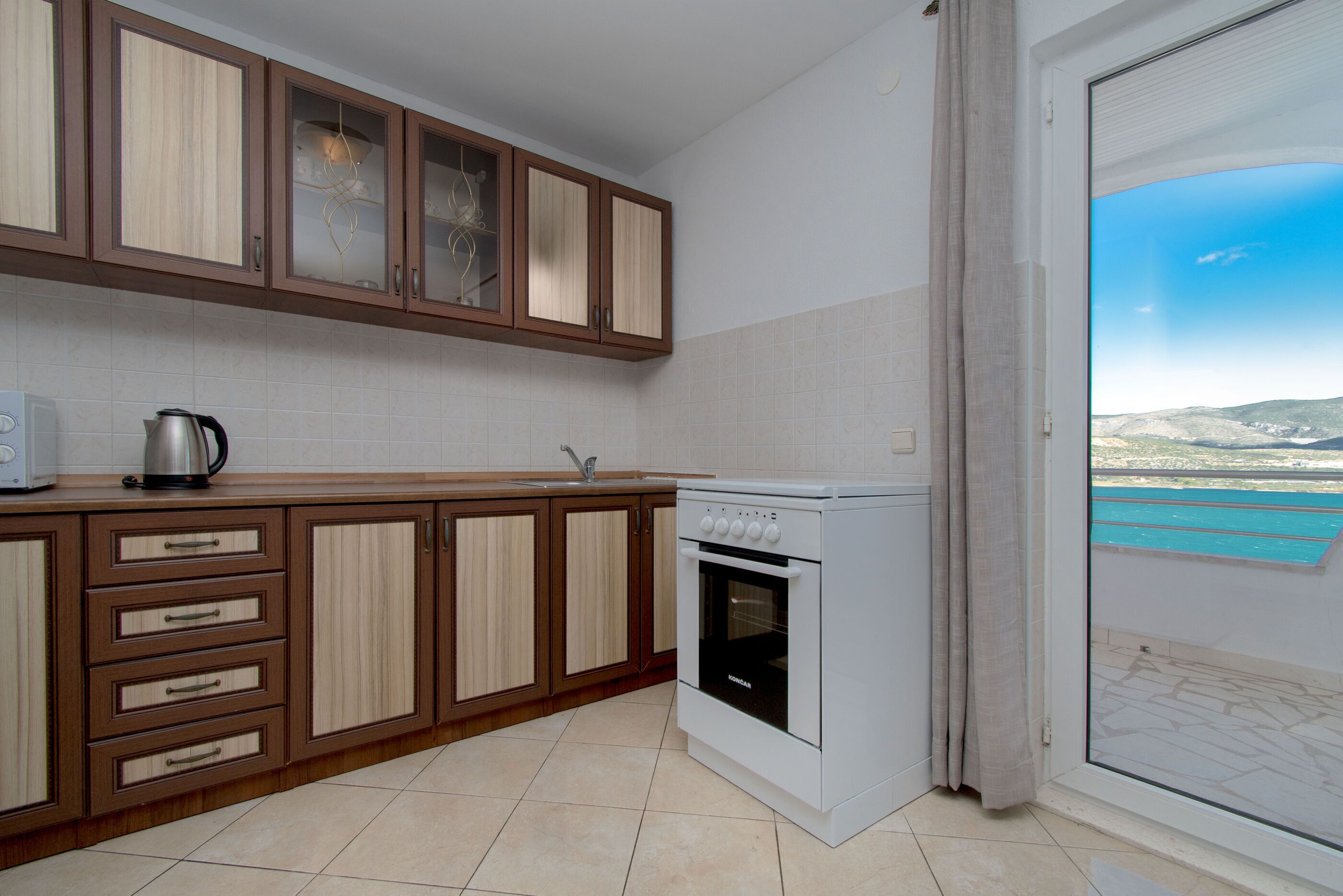 A kitchen with wooden cabinets, a white stove, and a view through a sliding door.