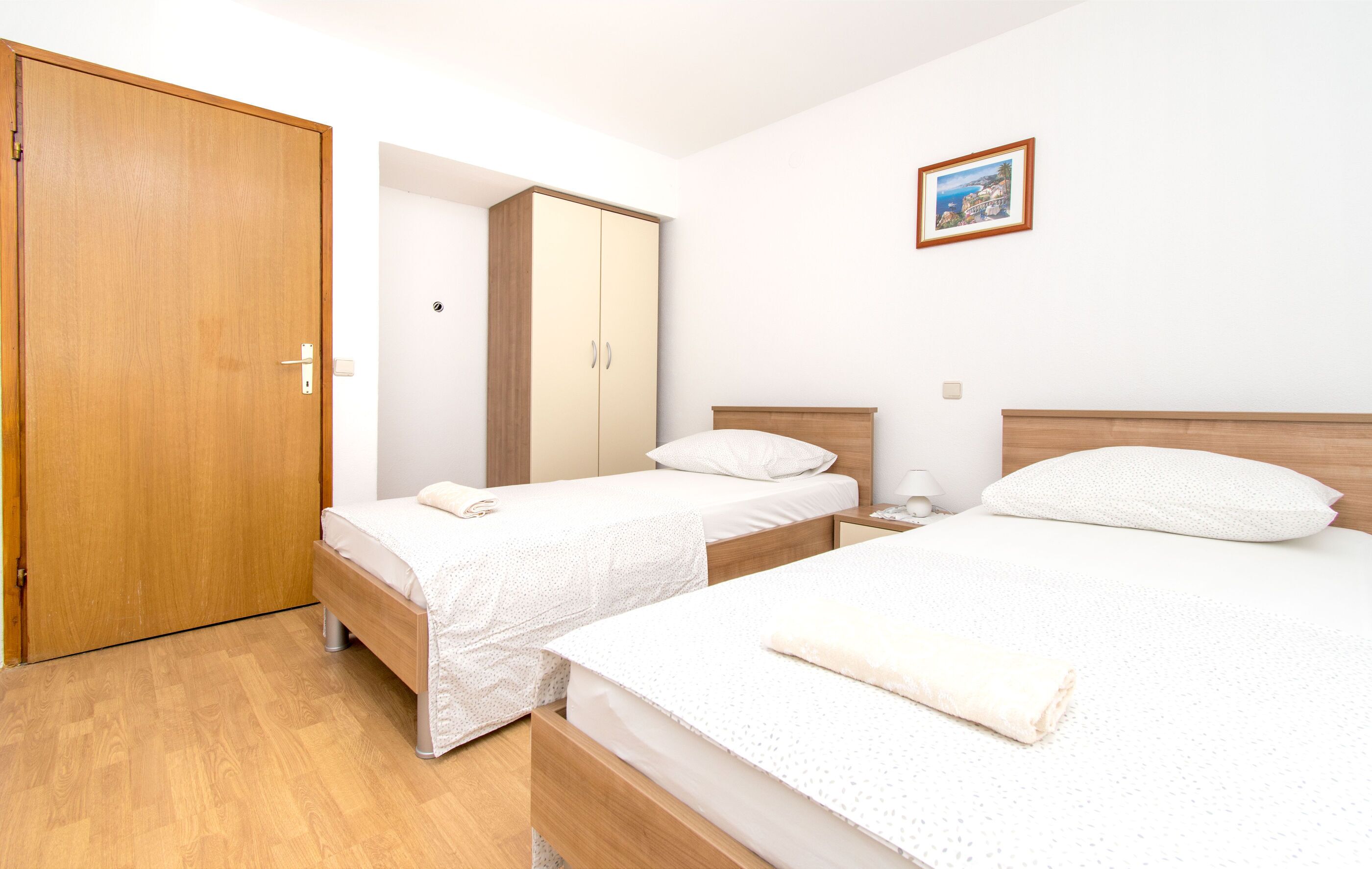 Un dormitorio con dos camas, un armario y una mesita de noche.