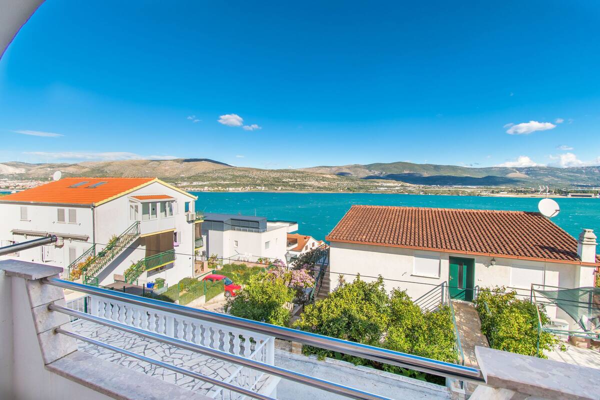 Une ville côtière avec des bâtiments donnant sur la mer, un escalier et un ciel bleu dégagé.