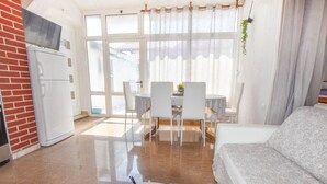Una cocina moderna con refrigerador, un comedor con mesa y sillas, y un sofá.