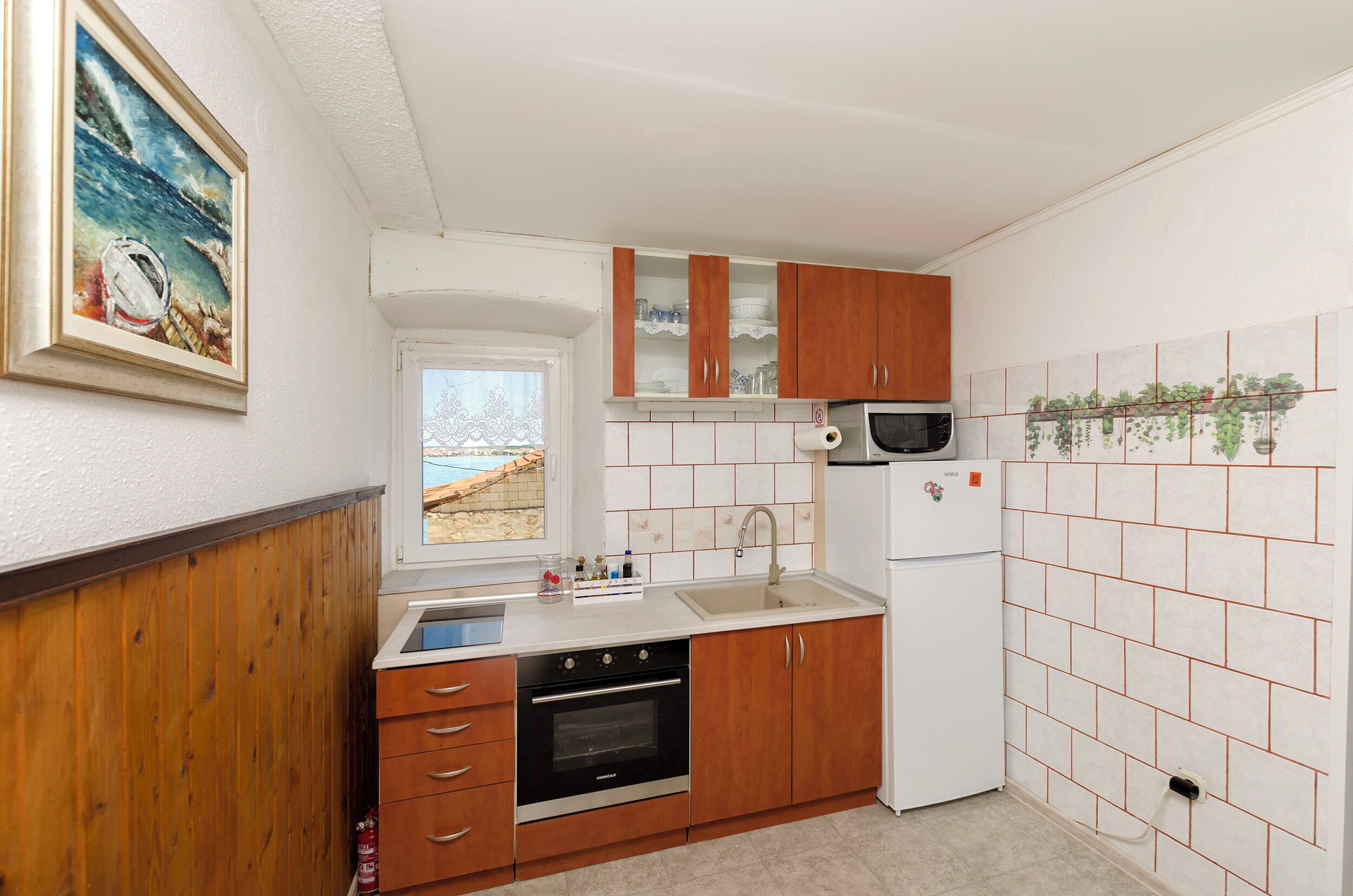 A compact kitchen with wooden cabinets, a built-in oven, a microwave, and a tiled backsplash.