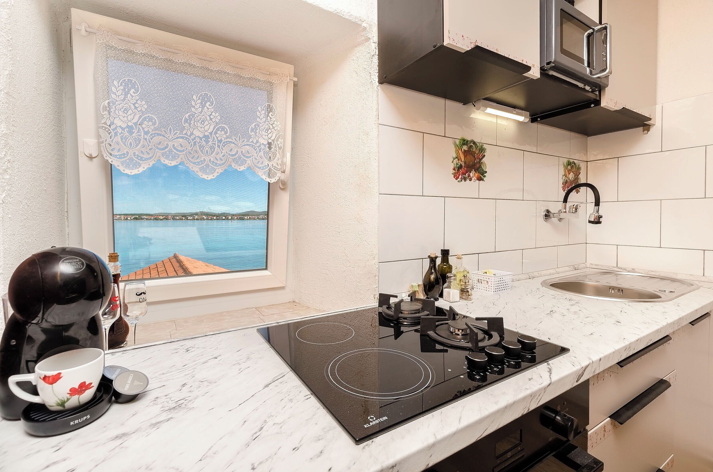 A kitchen with a stove, sink, and window with a view of a body of water.