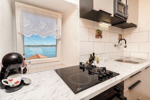 Una cucina con fornello, lavandino e finestra vista mare.
