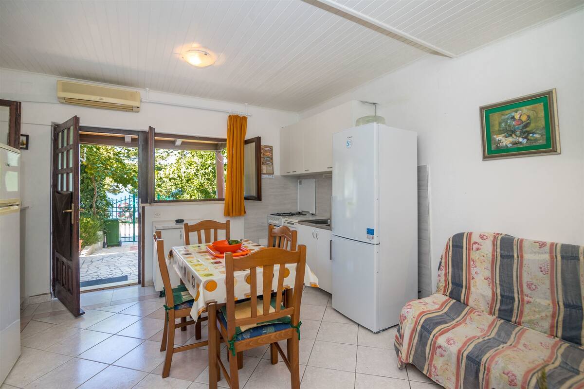 Une cuisine de taille réduite comprenant un réfrigérateur, une table à manger avec des chaises et un canapé.