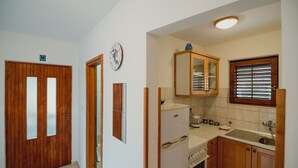 A compact kitchen with wooden cabinets, a refrigerator, a stove, and a sink. - Apartments Antun (Ivan Dolac)