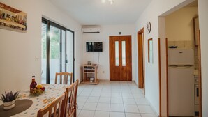 A compact kitchen with a dining area, a TV mounted on the wall, and a refrigerator. - Apartments Antun (Ivan Dolac)