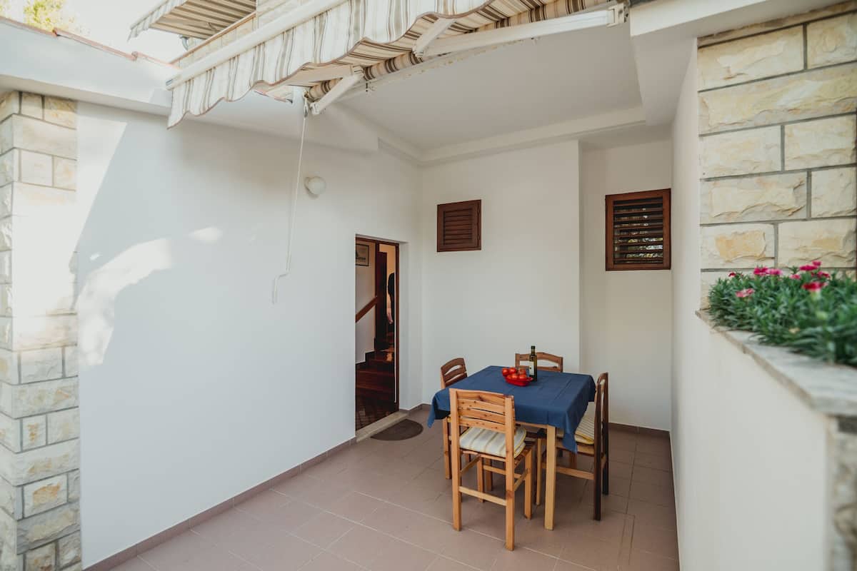 Un comedor con una mesa dispuesta para cuatro personas, una pared de piedra y una puerta de madera que da a otra habitación.