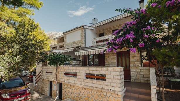 A two-story house with a stone facade, a balcony, and a car parked in front. - Apartments Antun (Ivan Dolac)