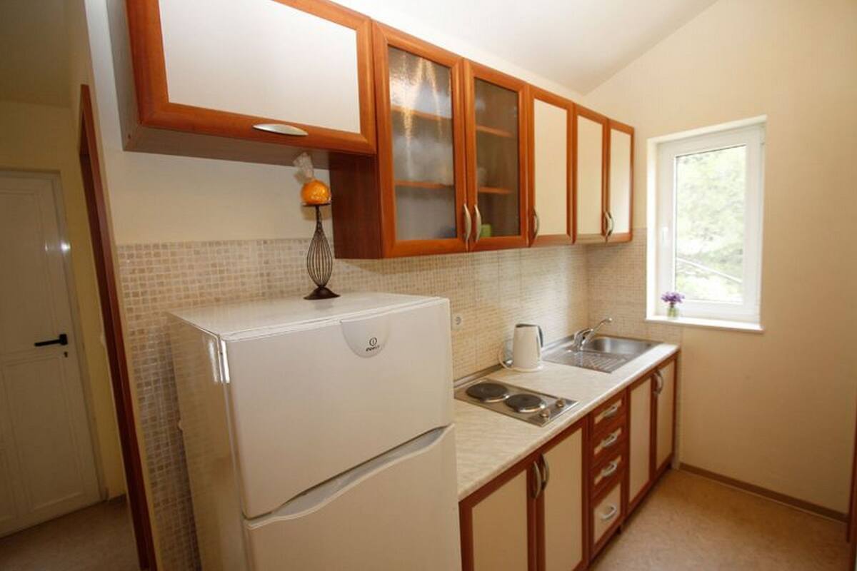 A kitchen with wooden cabinets, a white refrigerator, a sink, and a window with a view.
