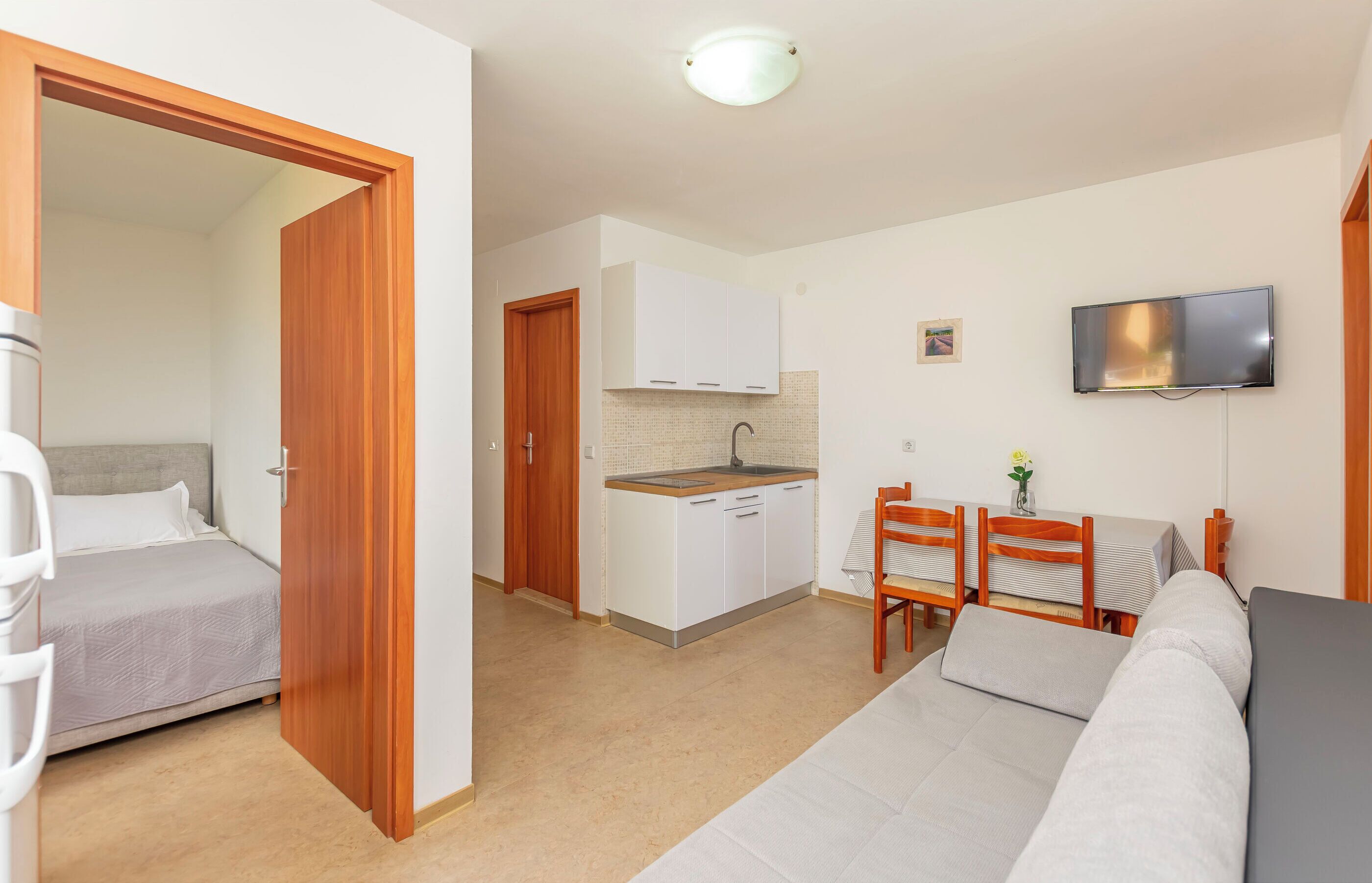 A compact living space with a kitchenette, a dining area, and a bedroom.