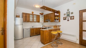 Eine Küche mit Holzausstattung, einem Edelstahlkühlschrank, einer Spüle und einem Barhocker.