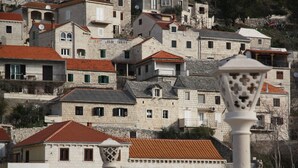 Un ensemble de bâtiments en pierre, coiffés de toits en tuiles rouges, dont certains sont dotés de balcons.