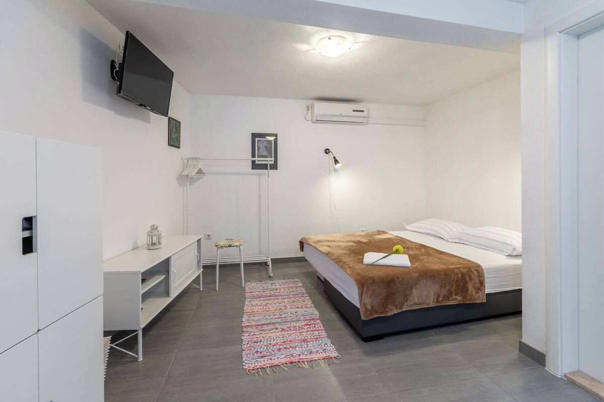 Une chambre moderne équipée d’un lit, d’un bureau, d’une chaise, d’un téléviseur et d’un appareil de climatisation.