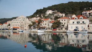 Une propriété située au bord de l’eau, comprenant plusieurs bâtiments, un quai avec des bateaux et une colline sur laquelle se trouvent des habitations.