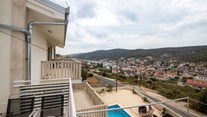 A balcony with a pool, overlooking a residential area with houses and hills. - Apartments Mirjana (Marina)
